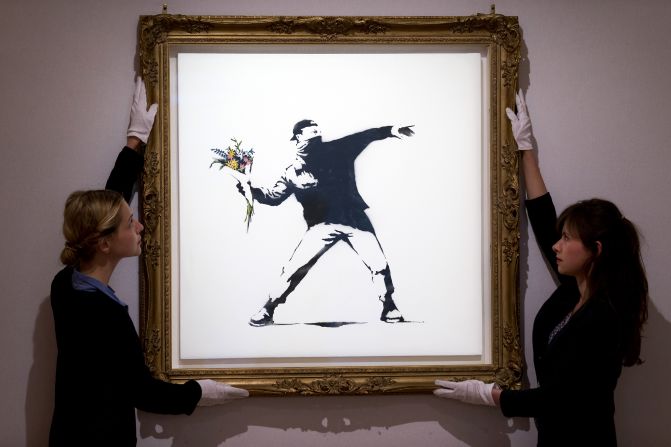 Las empleadas de la galería ajustan la obra "Love Is in the Air" antes de la subasta en Londres, el 24 de junio de 2013. La pieza se vendió por 248.776 dólares. 