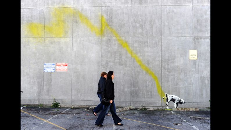 Un grupo de personas caminan al lado de una pintura de Bansky de un perro que orina en una pared en Beverly Hills, California, en 2011. 