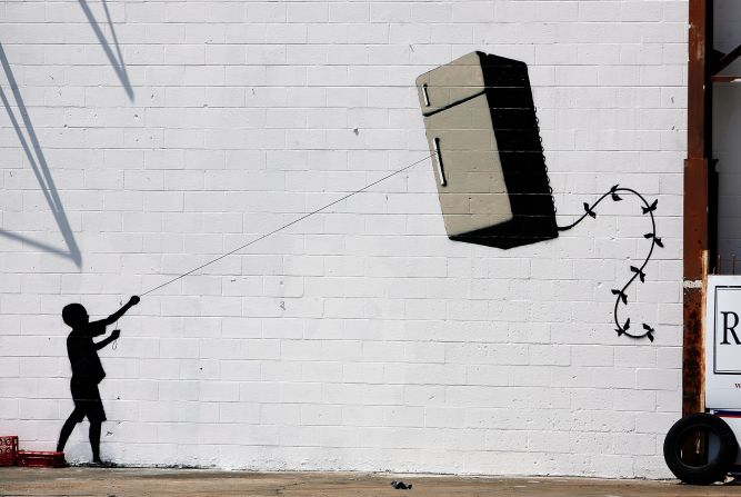 La silueta de un niño que sostiene una cometa en forma de refrigerador se ve en un muro de Nueva Orleans en 2008. 
