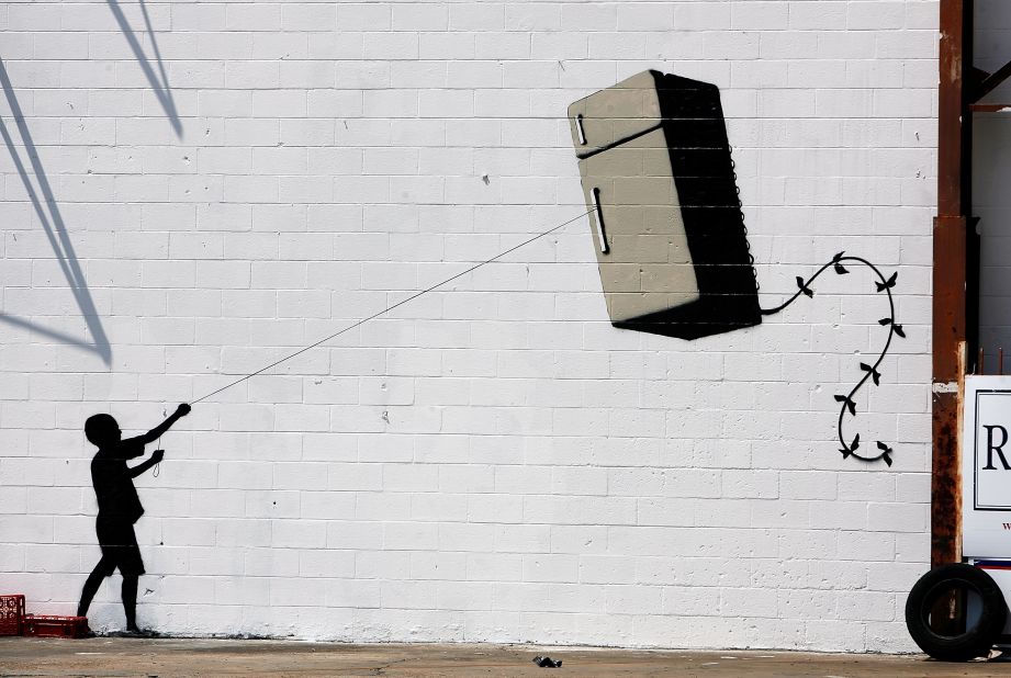 A silhouette of a child holding a refrigerator-shaped kite is seen on a wall in New Orleans in 2008.