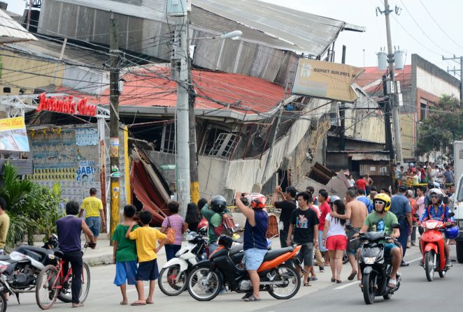 People gather outside damaged buildings in Cebu on October 15.