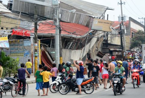 People gather outside damaged buildings in Cebu on October 15.