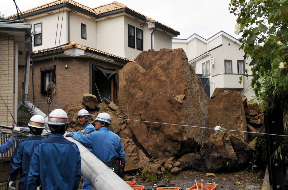 Rocks from a landslide down an electric pole outside a house in suburban Tokyo.