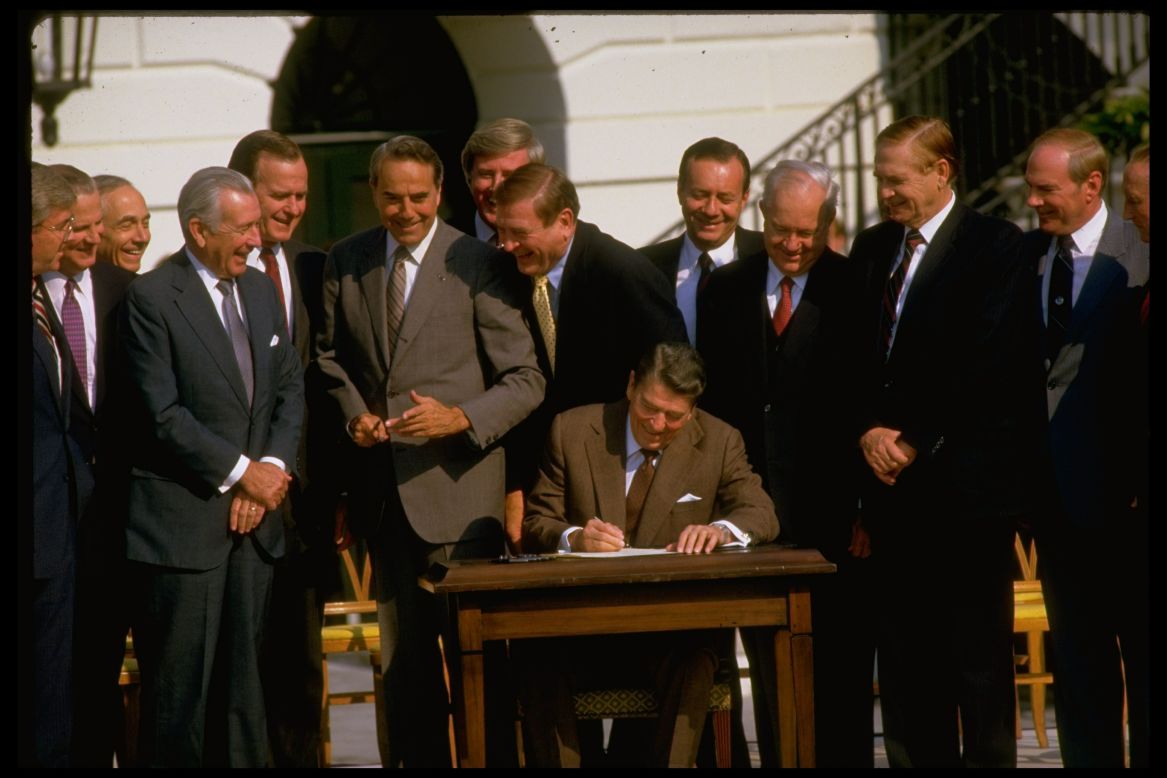 Reagan, surrounded by politicians, signs the Tax Reform Act of 1986. Democrats and Republicans sharply disagreed on how to amend the tax code, but both sides eventually compromised.