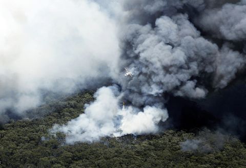 A helicopter works to extinguish bush fires burning near Winmalee on October 18.