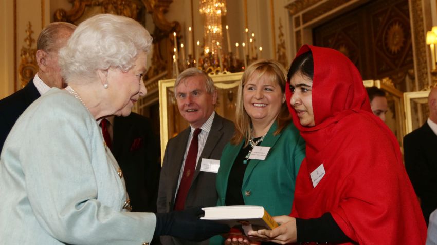 Malala Yousafzai gives a copy of her book to Britain's Queen Elizabeth II during a reception for youth, education and the Commonwealth at Buckingham Palace, London, Friday Oct. 18, 2013. The Pakistani teenager, an advocate for education for girls, survived a Taliban assassination attempt last year on her way home from school. (AP Photo/Yui Mok, Pool)