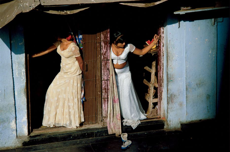 Jodi Cobb joined National Geographic as one of the magazine's first female staff photographers, in 1977. In this image she captures prostitutes, who are known as cage girls and are often sex slaves, displaying themselves on a Mumbai street.