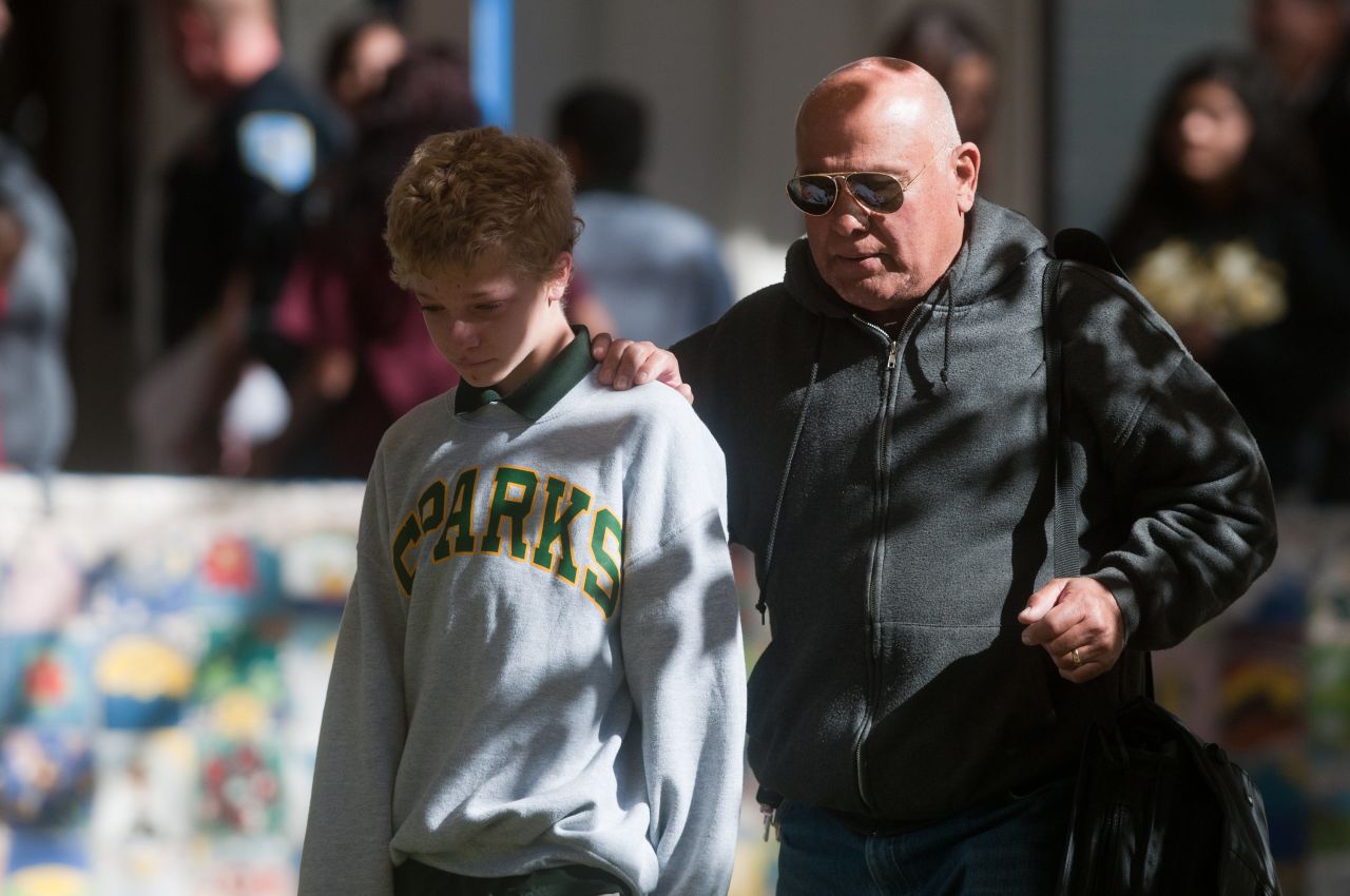 A parent escorts his child from Agnes Risley Elementary School after a shooting Monday, October 21, at nearby Sparks Middle School in Sparks, Nevada. A student opened fire at the middle school, police said, killing a teacher and wounding two students.