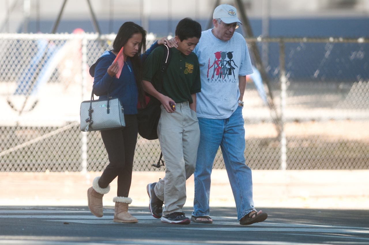 Parents escort a child from Agnes Risley Elementary School after the shooting.