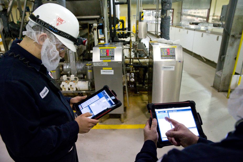 Technician Grimaldo Romero, left, uses his iPad to help maintain machinery at the World's Finest Chocolate plant in Chicago, Illinois, on March 21, 2013.