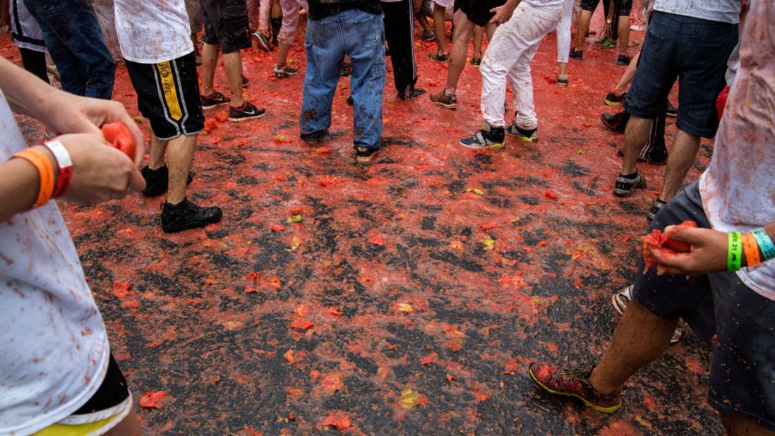 Participants slip and slide around the parking lot that was converted into the stage for the massive tomato fight.