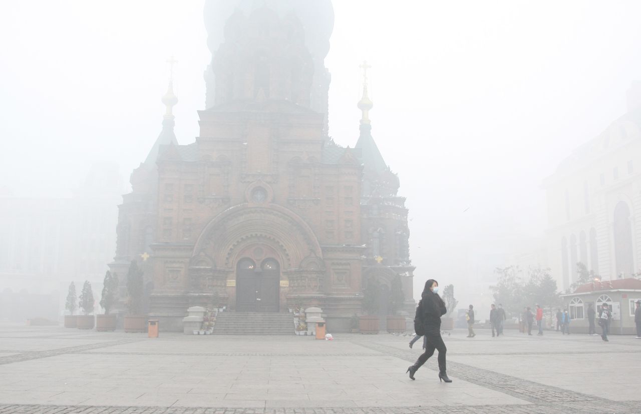 Una mujer usa una máscara mientras camina en una calle de Harbin.<br />Las escuelas, y las autopistas de la ciudad de Harbin, ubicada en el noreste de China, cerraron por una densa nube de contaminación que redujo la visibilidad.