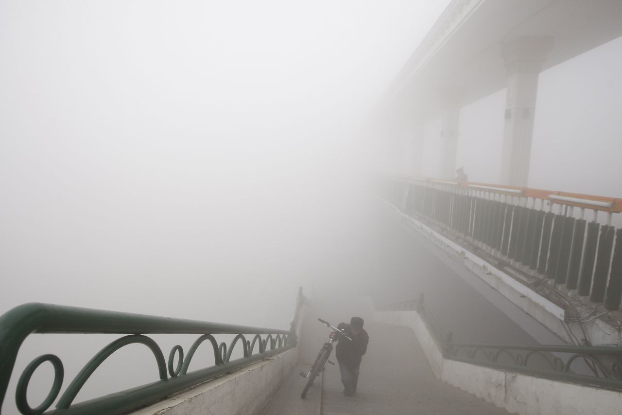 Un hombre empuja su bicicleta en un puente de Harbin. El gobierno dijo que el esmog se debe a la falta de viento y a la quema de carbón.
