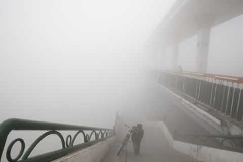 A man pushes his bike onto a Harbin bridge on October 21. Government officials blamed the smog on a lack of wind and farmers burning crop stalk after their autumn harvest. Harbin's coal-burning heating system, which was recently started, is also a likely factor.