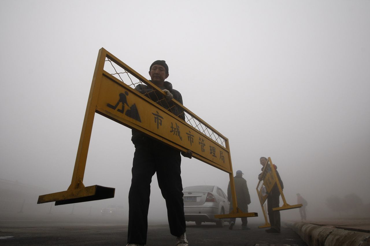 Un trabajador lleva una barrera vial en Harbin.