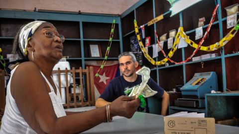 A shopkeeper talks to a customer in Santiago de Cuba, on July 10. Cuban government plans to end the dual-currency system.