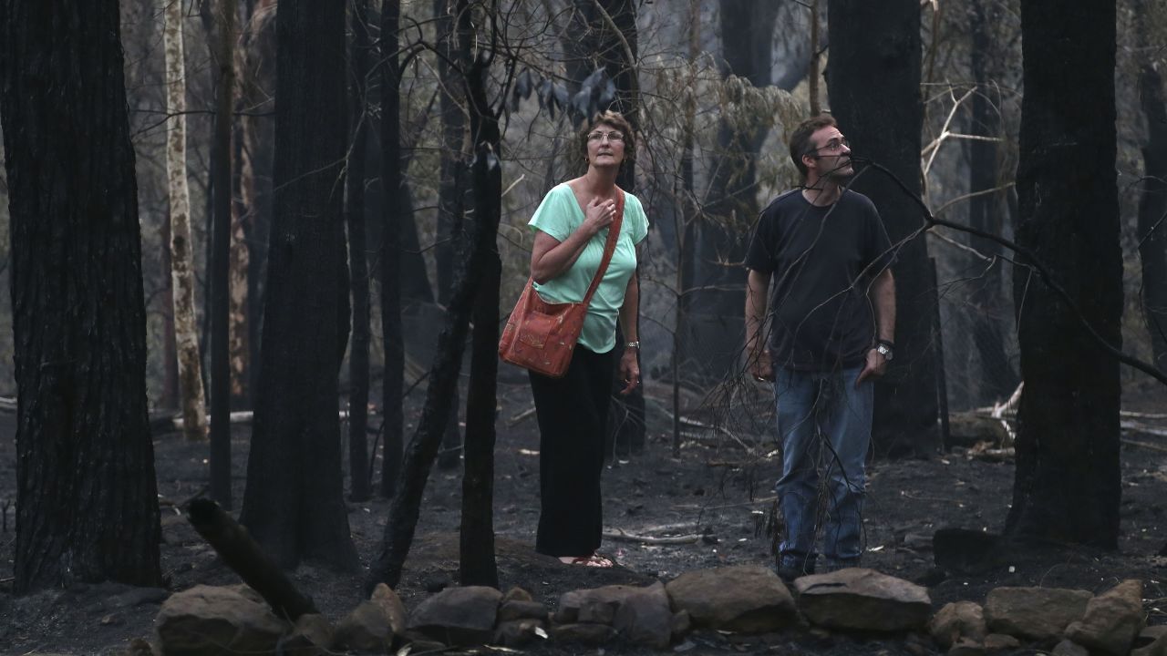 People walk around the area behind their destroyed home in Winmalee on October 22.