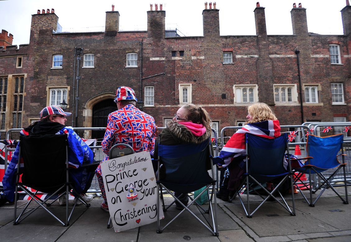 Spectators sit across from St. James' Palace as they wait for the royal family to arrive for the christening. 
