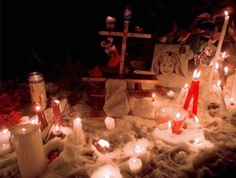 Candles surround a portrait of JonBenet outside her Boulder home after a candlelight vigil on the one-year anniversary of her murder on December 26, 1997. A year after the murder, Boulder police indicated John and Patsy Ramsey were under "an umbrella of suspicion," and would  be questioned again.