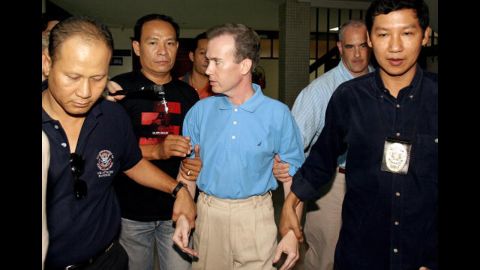 Thai police officials escort U.S. teacher John Mark Karr at the Thai Immigration Department in Bangkok on August 17, 2006. Officials announced Karr as a suspect in the case. Karr said he was present when JonBenet died, and that he loved her and her death was an accident. On August 26, 2006, the Boulder County District Attorney decided not to charge Karr in connection with the murder after DNA tests confirmed that he wasn't a match to the evidence found at the crime scene.