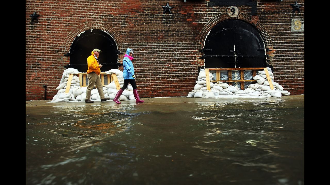 People walk past sandbags on a flooded street in the Red Hook section of Brooklyn, New York, as Hurricane Sandy moves closer to the area on October 29, 2012.