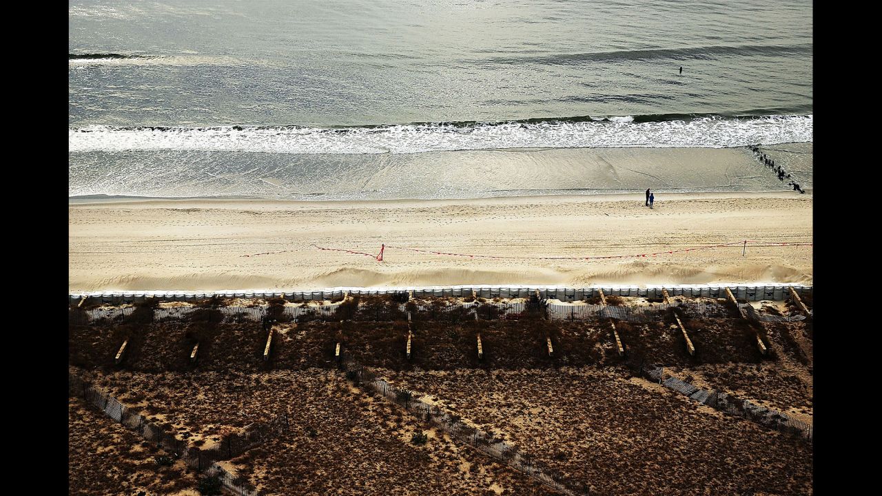 Two people walk along the beach where the boardwalk once stood on October 20 in Rockaway.