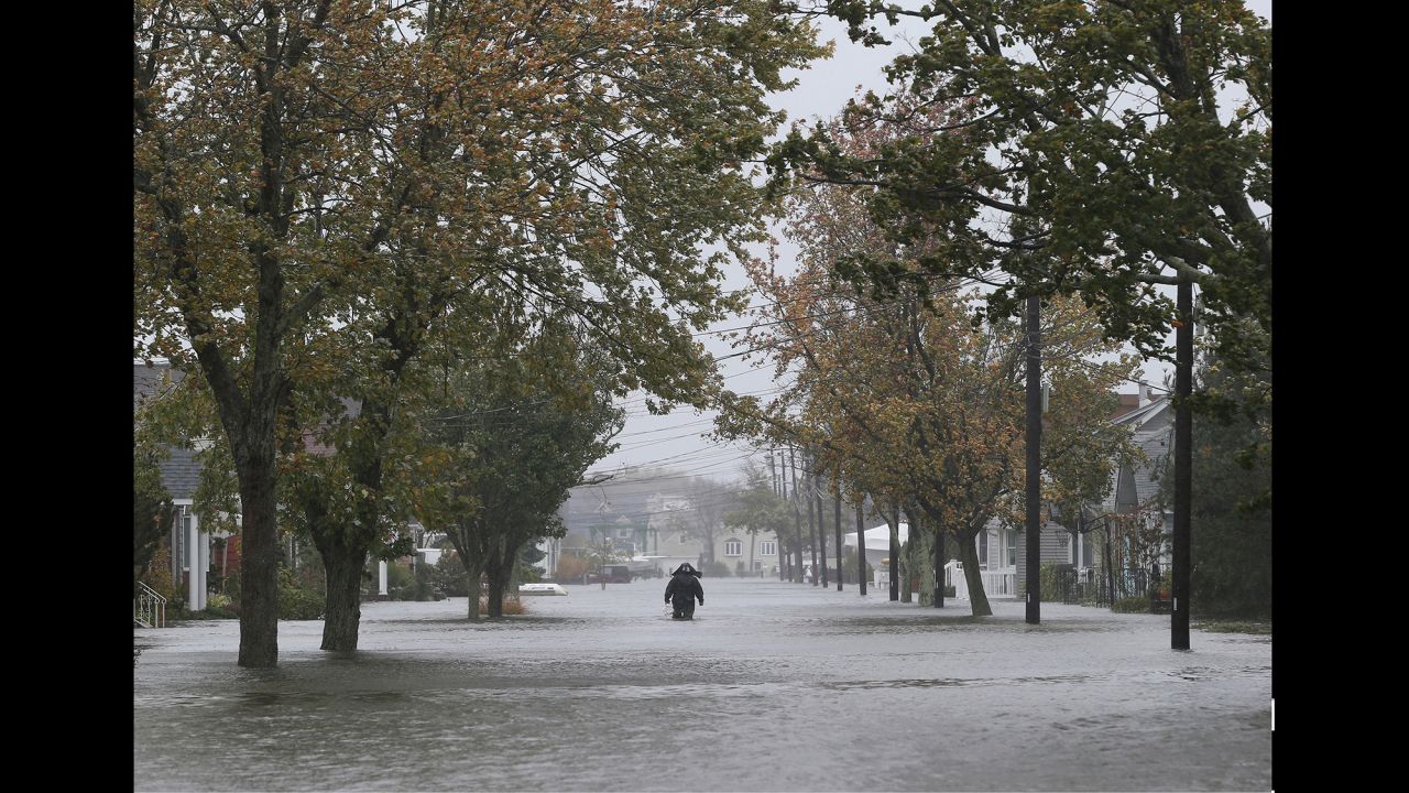  A person walks down South 9th Street in Lindenhurst, New York, as high tide, rain and winds flood area streets on October 29, 2012.