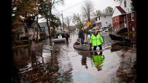 An emergency worker uses a boat to help two people evacuate after their neighborhood was flooded on October 30, 2012, in Little Ferry, New Jersey. 