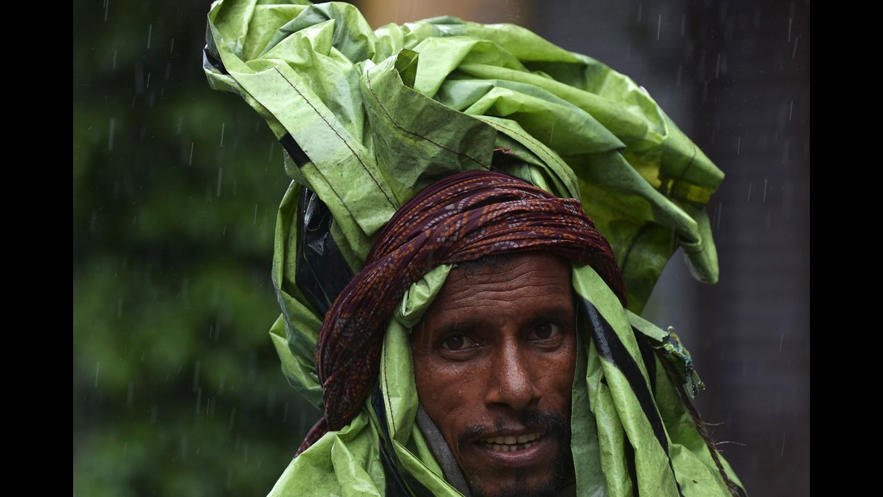 An Indian rickshaw puller covered with plastic walks through a street during the heavy rains in Kolkata, India, on Saturday, October 26. Earlier this month, a cyclone struck the eastern coast and is now involved with mass flooding that has forced thousands to flee their homes and seek refuge in shelters.  
