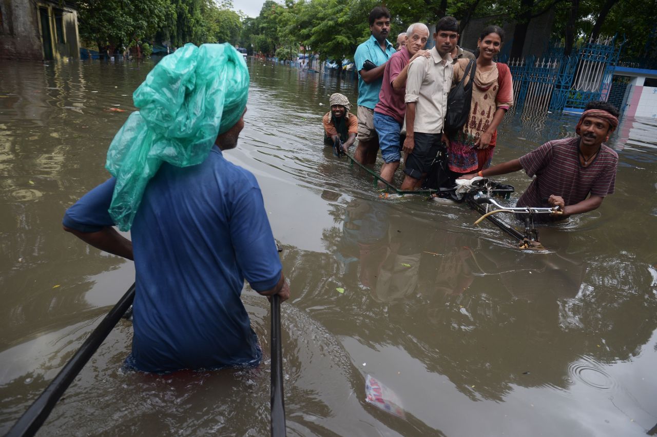 Indian rickshaw pullers carry passengers through a flooded street in Kolkata on October 26.