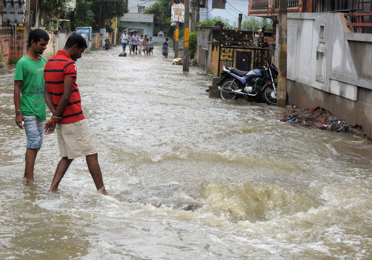 Pedestrians wade on a flooded street following heavy rain in Saroornagar on October 25.