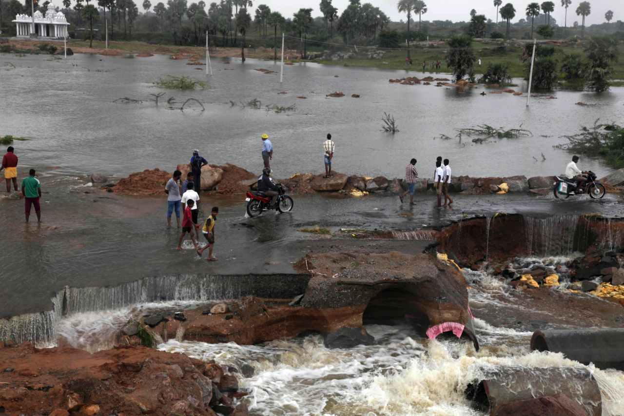People wade through a flood-damaged road on the outskirts of Hyderabad on October 26.