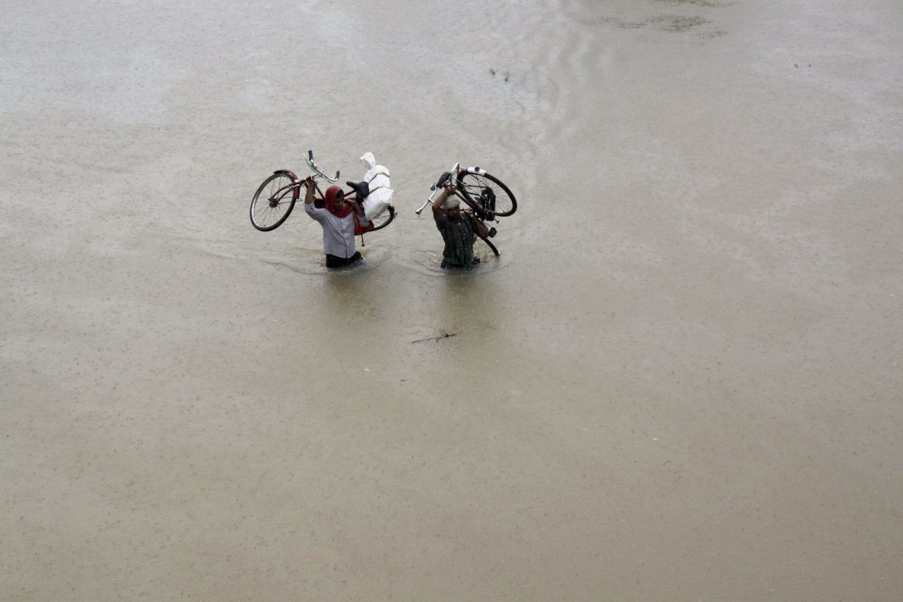 Two villagers carry their bicycles and wade through floodwaters in Banapur village in the eastern Indian state of Orissa on October 25.