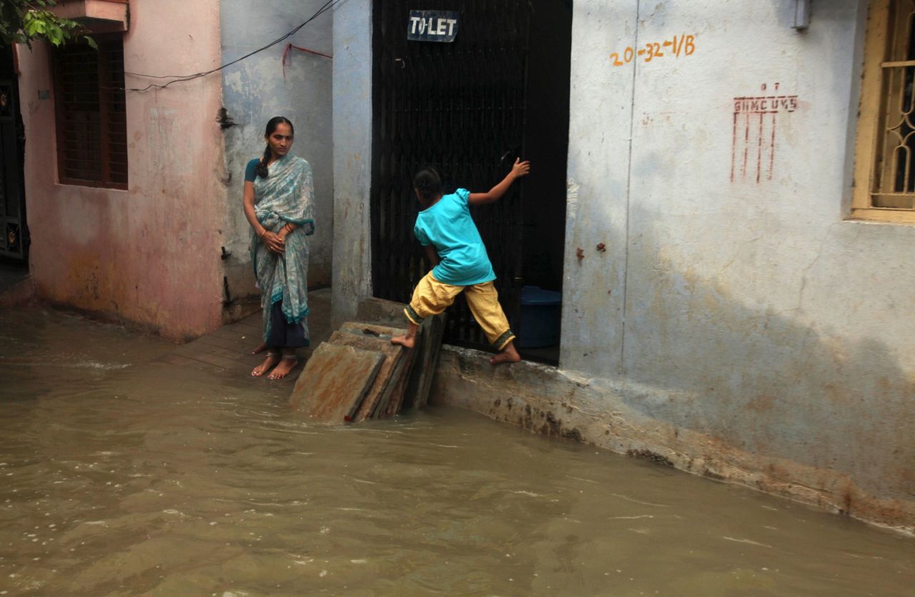 A child balances herself on dry area as she crosses a flooded street in Hyderabad on October 25.