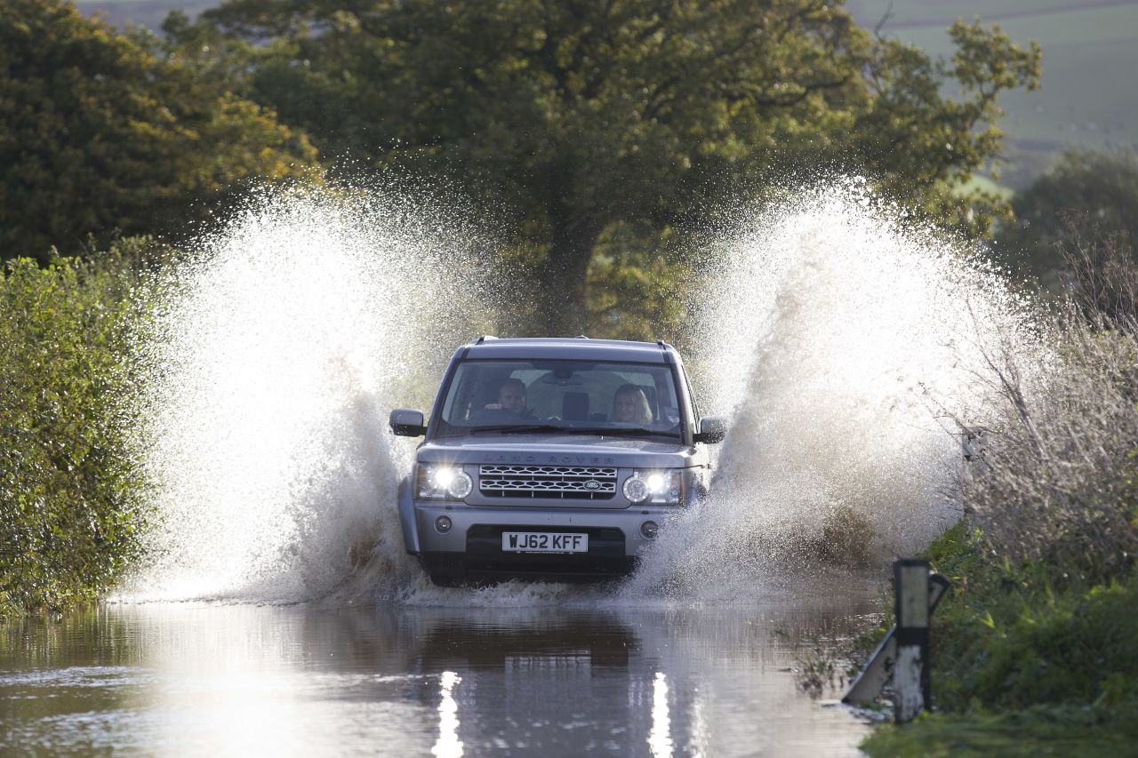 A vehicle splashes through a flooded section of road near the English village of Whitford on Monday.