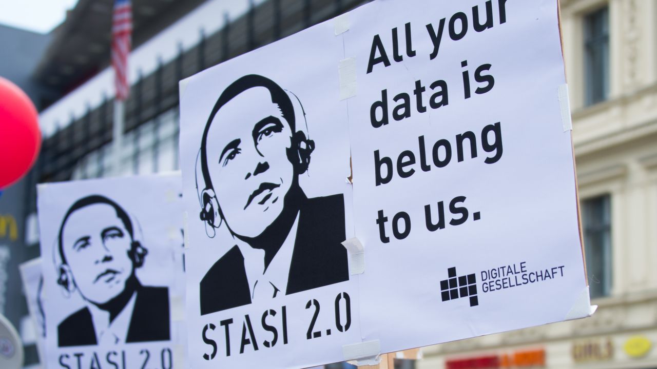 German protestors hold posters reading 'Stasi 2.0' depicting US President Barack Obama wearing headphones.