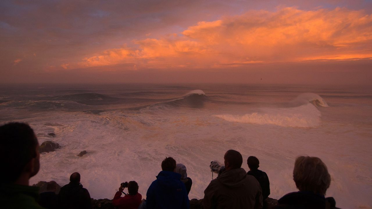 Photographers watch the sunrise at Praia do Norte. 