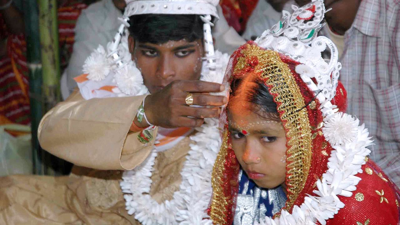 An Indian groom puts the holy mark on the forehead of his underage bride during a mass marriage program in 2006.