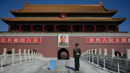 A paramilitary policeman stands before a portrait of Mao Zedong (back C) at Tiananmen Gate and the Forbidden City in Beijing on October 29, 2013.
