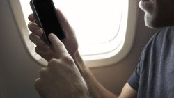 Man Uses Smart Phone Sitting in Airplane Window Seat