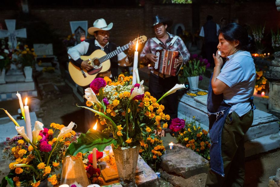 A Mexican woman wipes away a tear as a Mariachi band plays at the tomb of a loved one during the Dia de los Muertos, or Day of the Dead, festival in Oaxaca, Mexico, on Thursday, October 31. Celebrated in Mexico and around the world, the traditional holiday honors the lives of lost family members and friends.