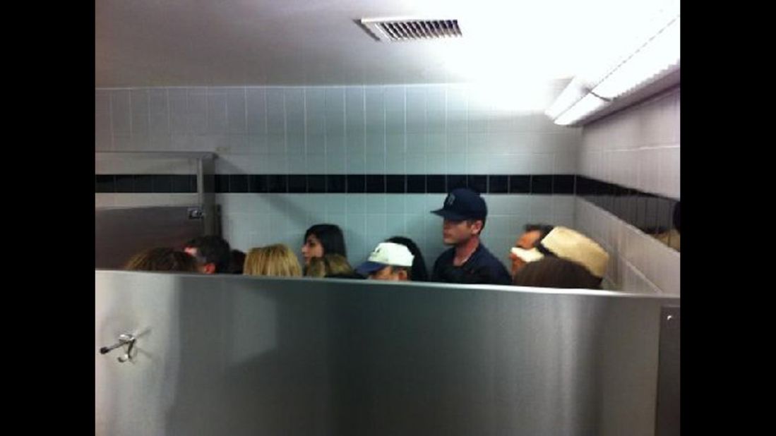 People hide inside a bathroom stall at the airport after the gunshots were reported.