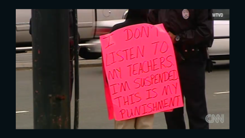 A North Carolina mom punishes her son for being suspended from school by having him wear a sign on a busy street.