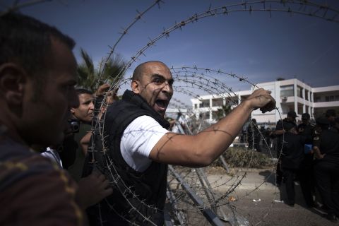 A Morsy supporter shouts at a police officer in Cairo. More than 100 pro-Morsy demonstrators faced a cordon of security forces behind barbed wire.