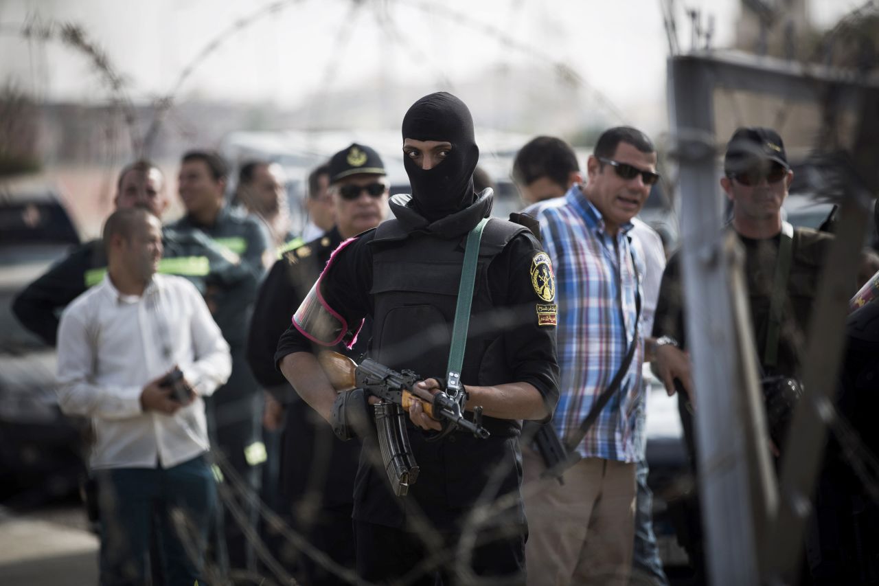 A masked police officer stands guard outside of the police academy compound where Morsy's trial was held.