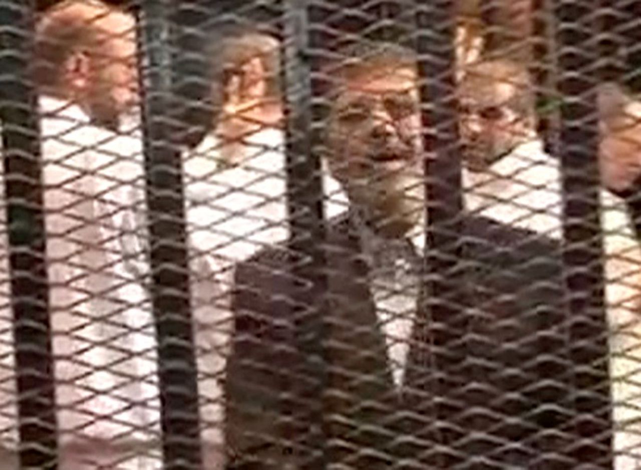 This image, made from video provided by Egypt's Interior Ministry, shows Morsy speaking from the defendant's cage as he stands with co-defendants during his hearing. "I am Dr. Mohamed Morsy, the President of the republic," Morsy said. "The coup is a crime and ... treason."