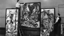 Two men prepare to hang German Expressionist painter Max Beckmann's triptych 'Temptation' at the 20th Century German Art Exhibition at the New Burlington Galleries, London. The exhibition includes work by all the German artists pilloried by Adolf Hitler in the 'Degenerate Art' exhibition in Munich of 1937. (Photo by Topical Press Agency/Getty Images)