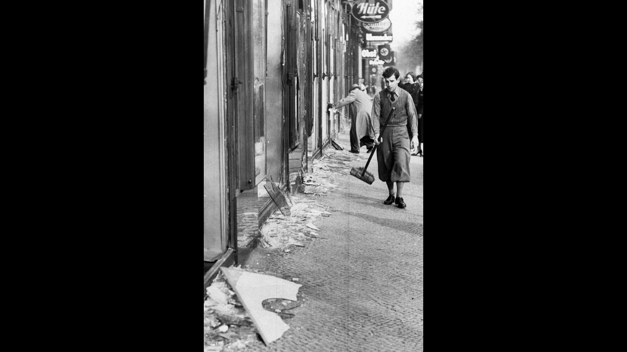 A young man prepares to clean up broken window glass in Berlin. During "Kristallnacht," about 30,000 Jewish men between the ages of 16 and 60 were arrested and taken to concentration camps.