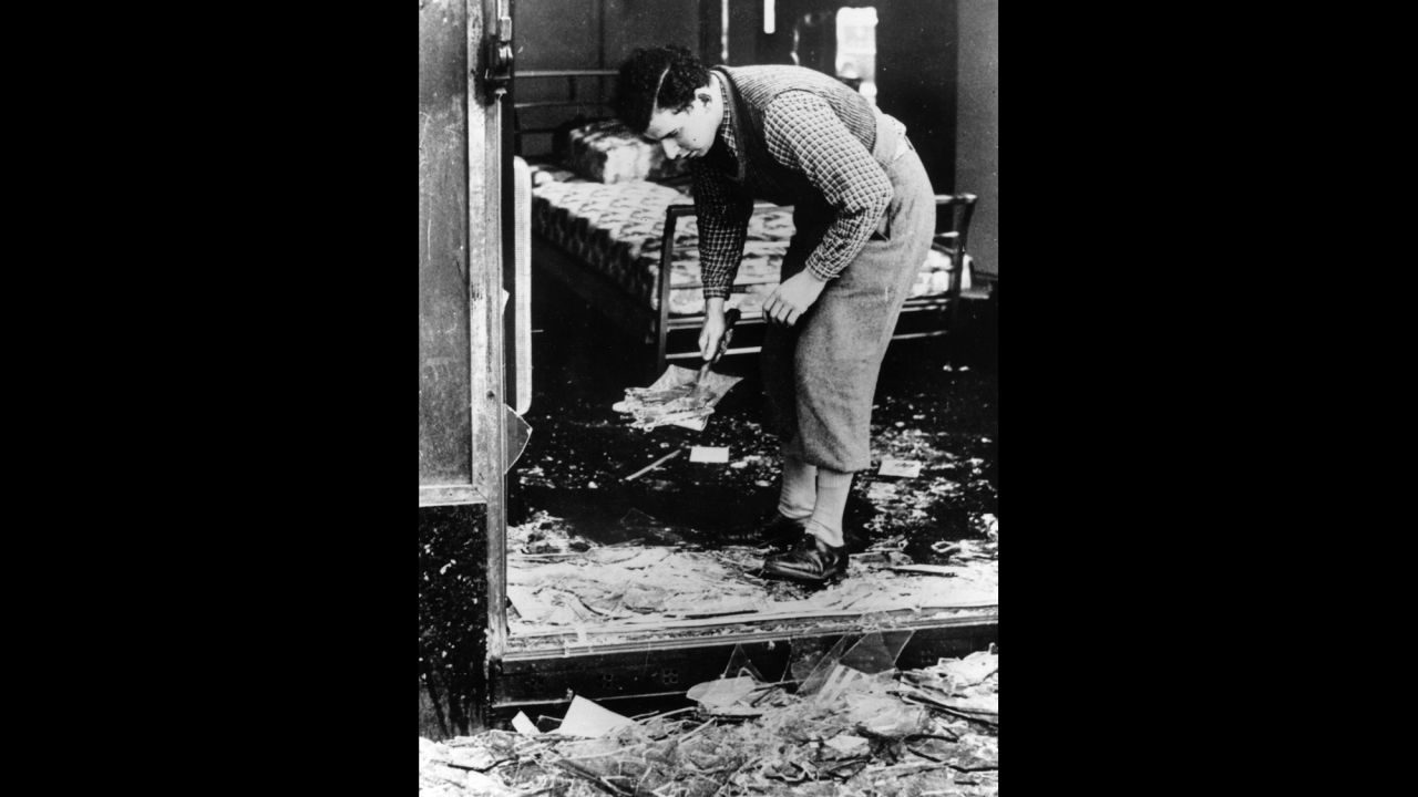 A young man clears broken glass from a Jewish-owned shop in Berlin.