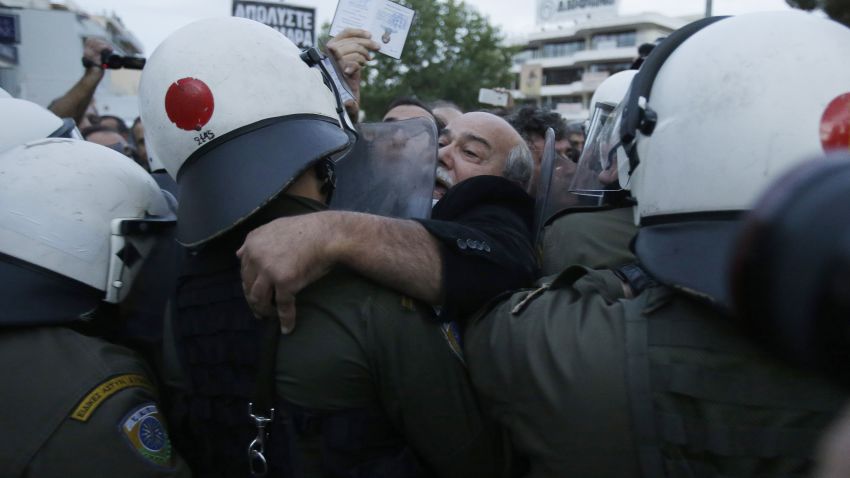 Parliament Member of Syriza, main opposition party Nikos Voutsis scuffles with police as he tries to pass from a block near ERT's headquarters in the northern Athens suburb of Agia Paraskevi, Greece early Thursday, Nov. 7, 2013.